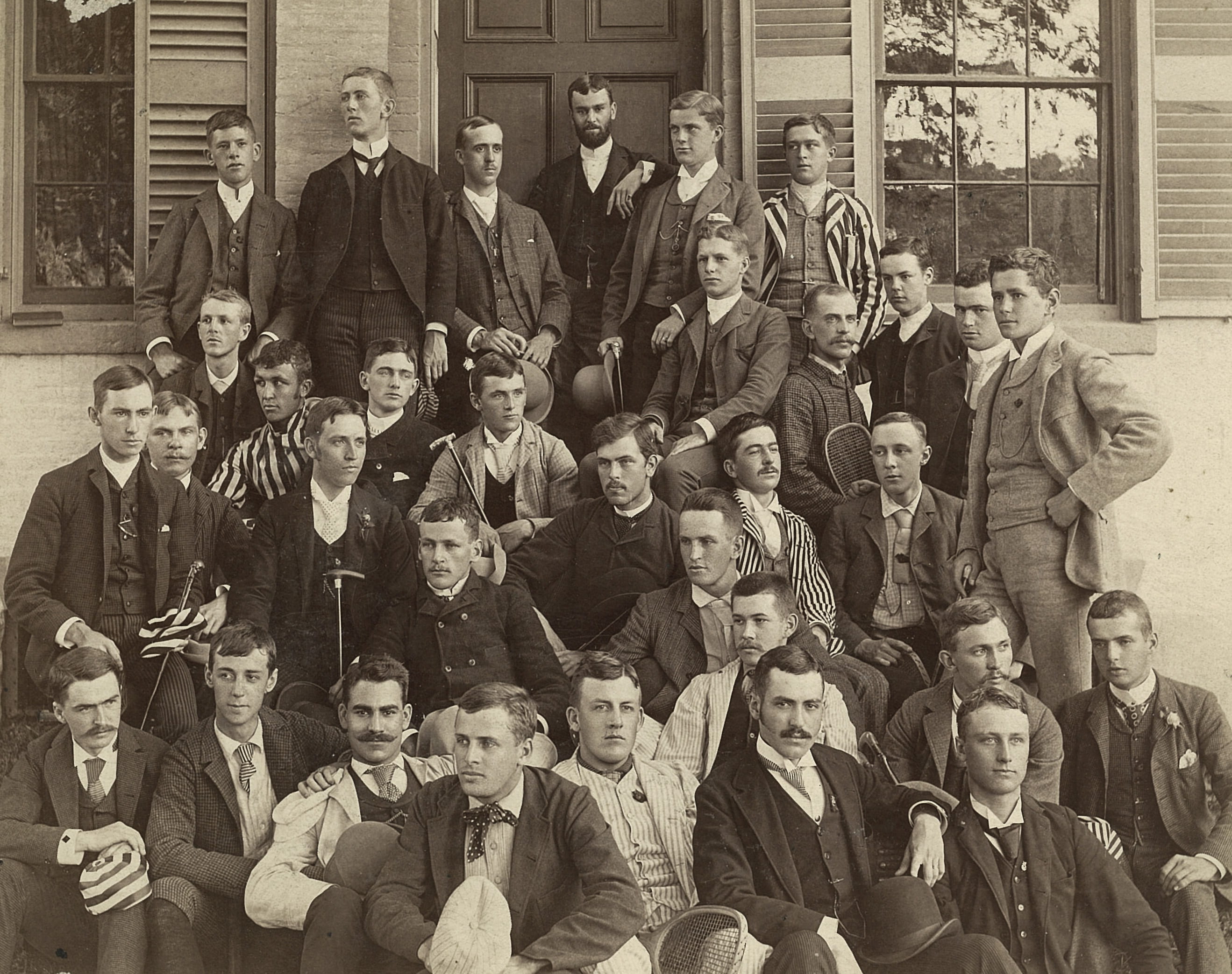 Photograph of a large group of young men in a variety of fashions. Most of the men are looking off the side of the picture with sultry expressions.