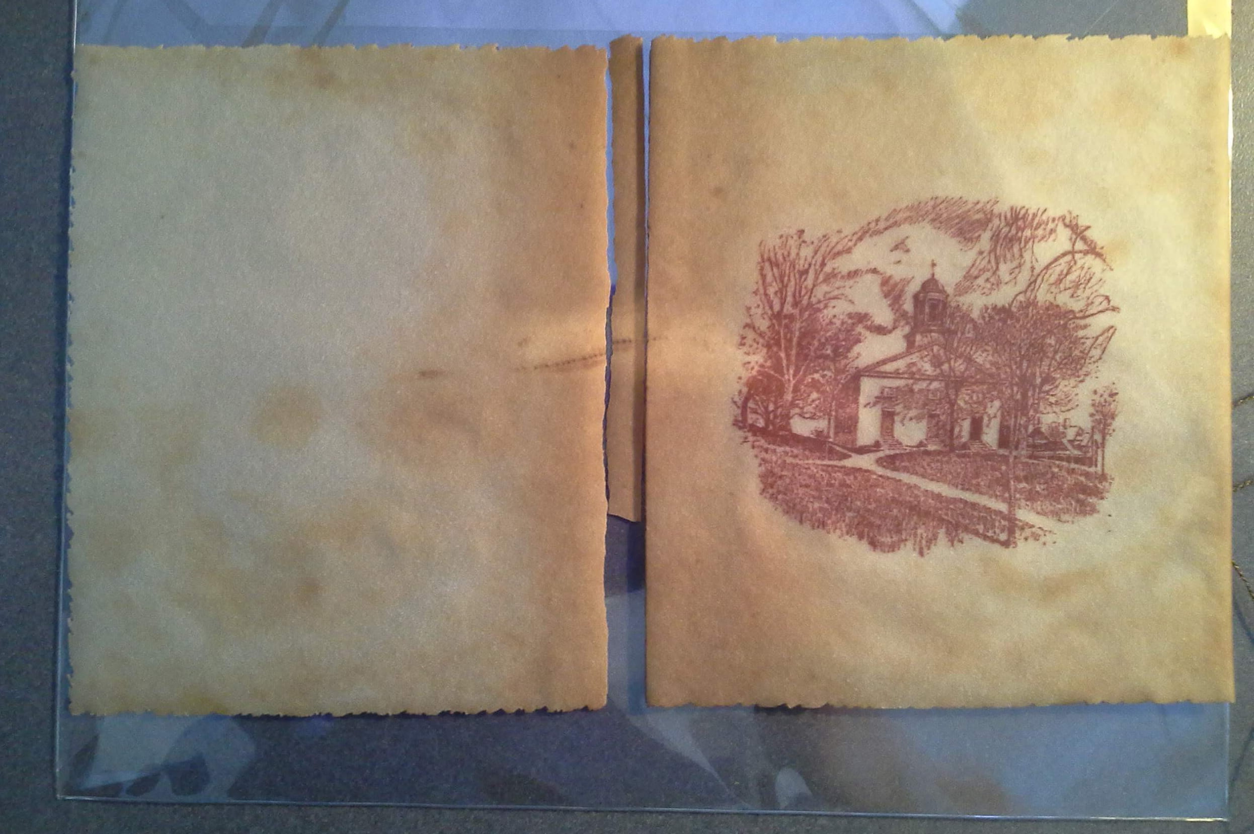 A picture of College Hall is printed in purple ink on a light brown piece of material, about 14 inches wide. The piece is broken halfway across, where the material was folded like a book cover.