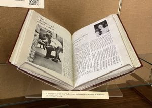 A book propped open in a display case, showing the headline "Coeducation at Amherst: A Feminine View"