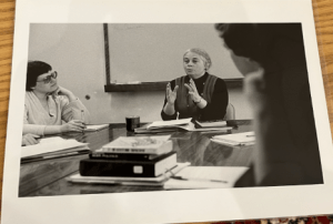 A black-and-white photograph of Rose Olver speaking in a classroom