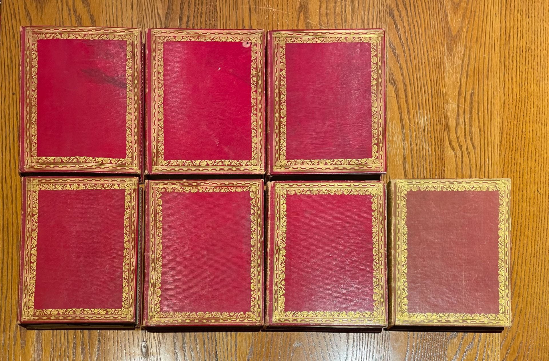 Seven red volumes with guilt edging.